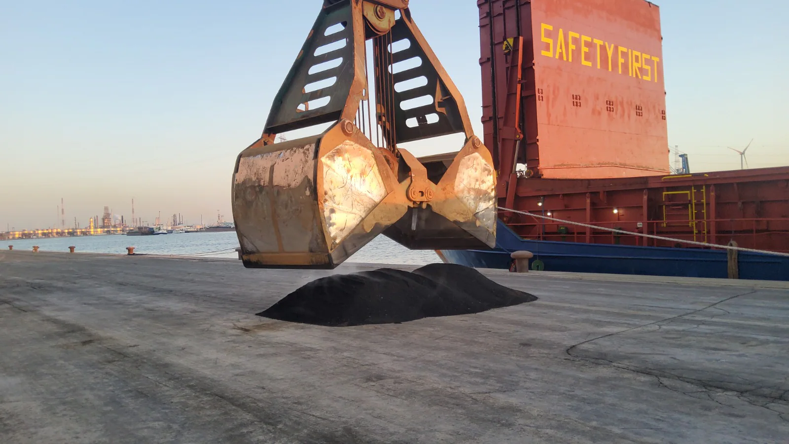 Crane grab moving bulk cargo during vessel discharge supervision