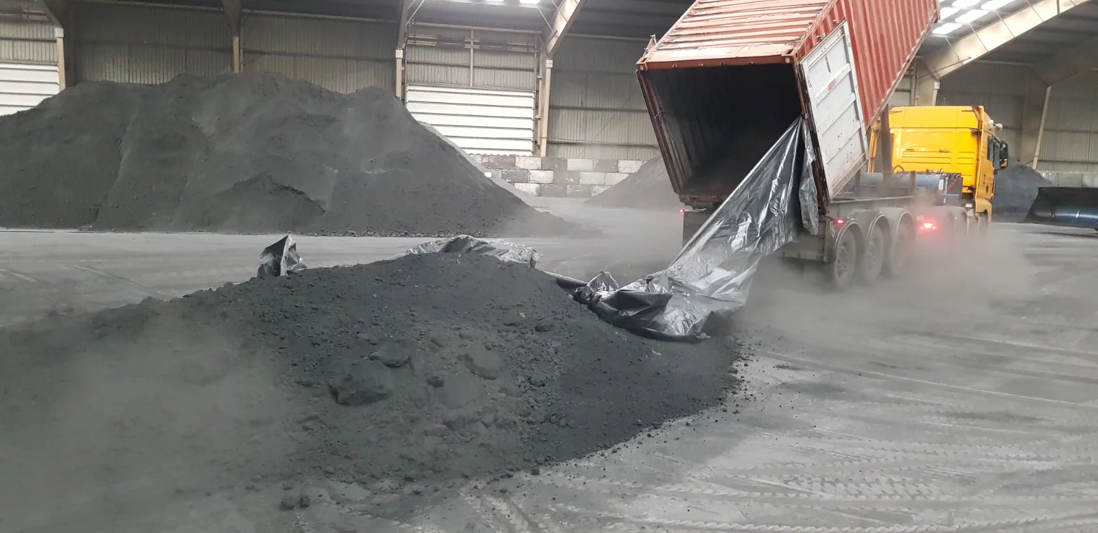 Lead concentrate being discharged from a container in a warehouse